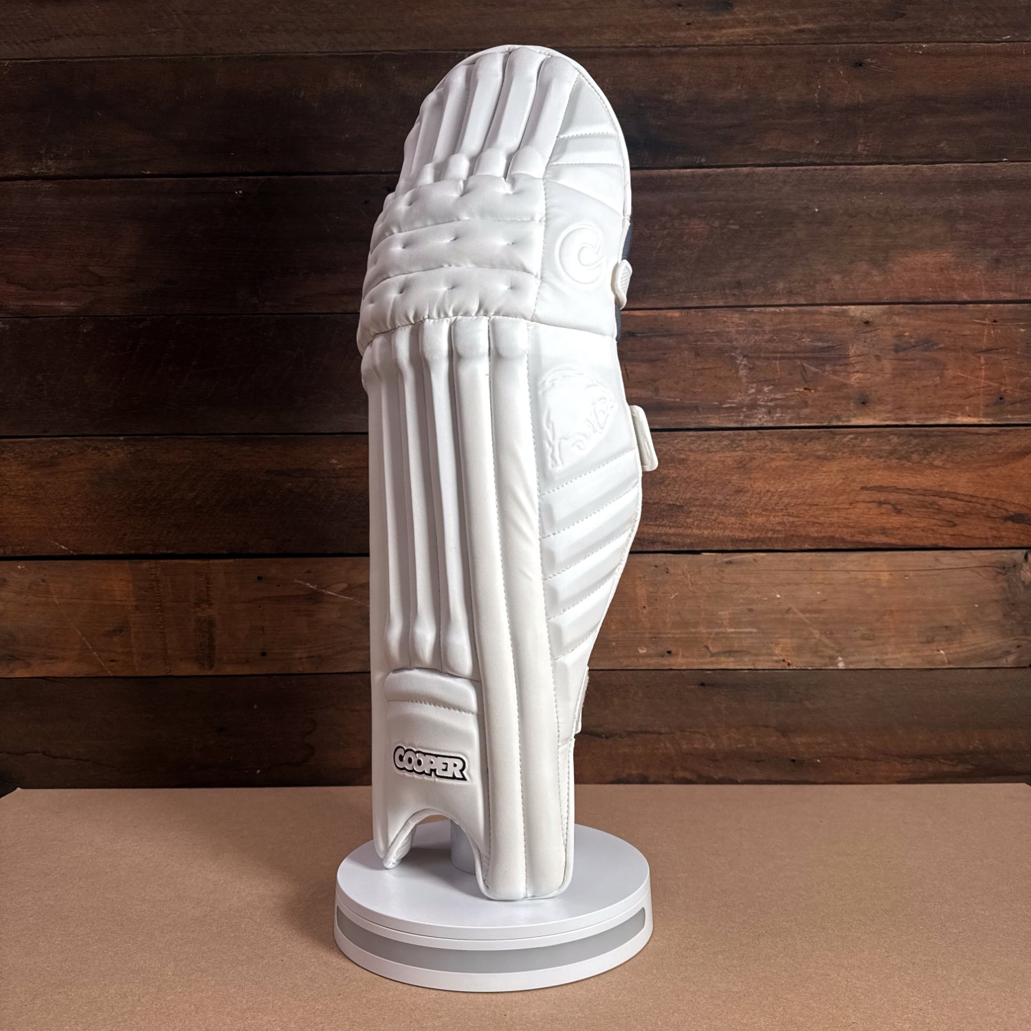 Bison cricket pads displayed on a stand, featuring premium foam design for optimal protection and comfort.