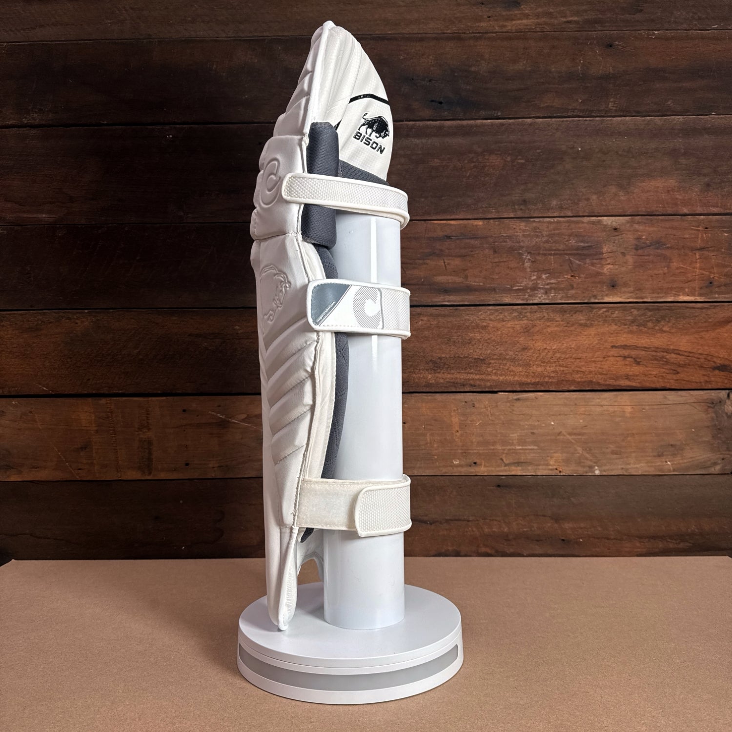 Bison youth cricket pads displayed on a stand, showcasing premium foam construction and sleek design for protection.