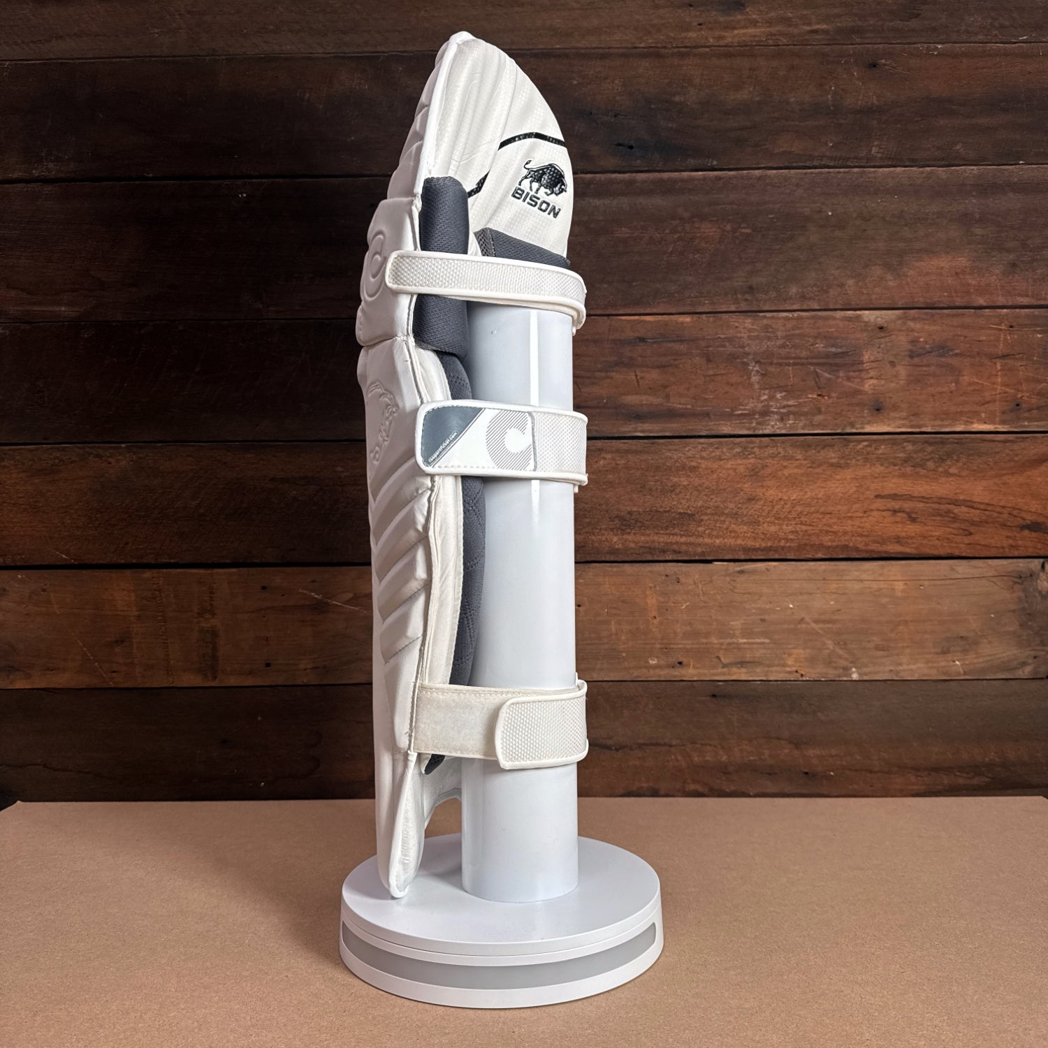 Bison youth cricket pads displayed on a stand, showcasing premium protection and modern design for performance.