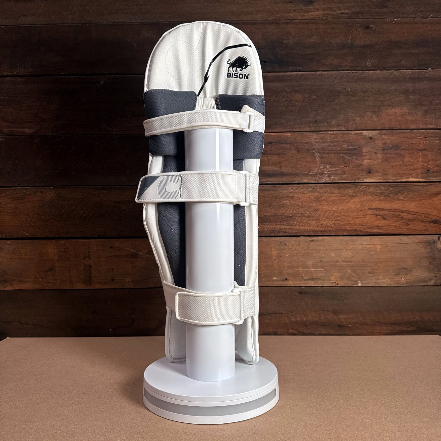 Bison youth cricket pads displaying premium foam protection and adjustable straps on a display stand.