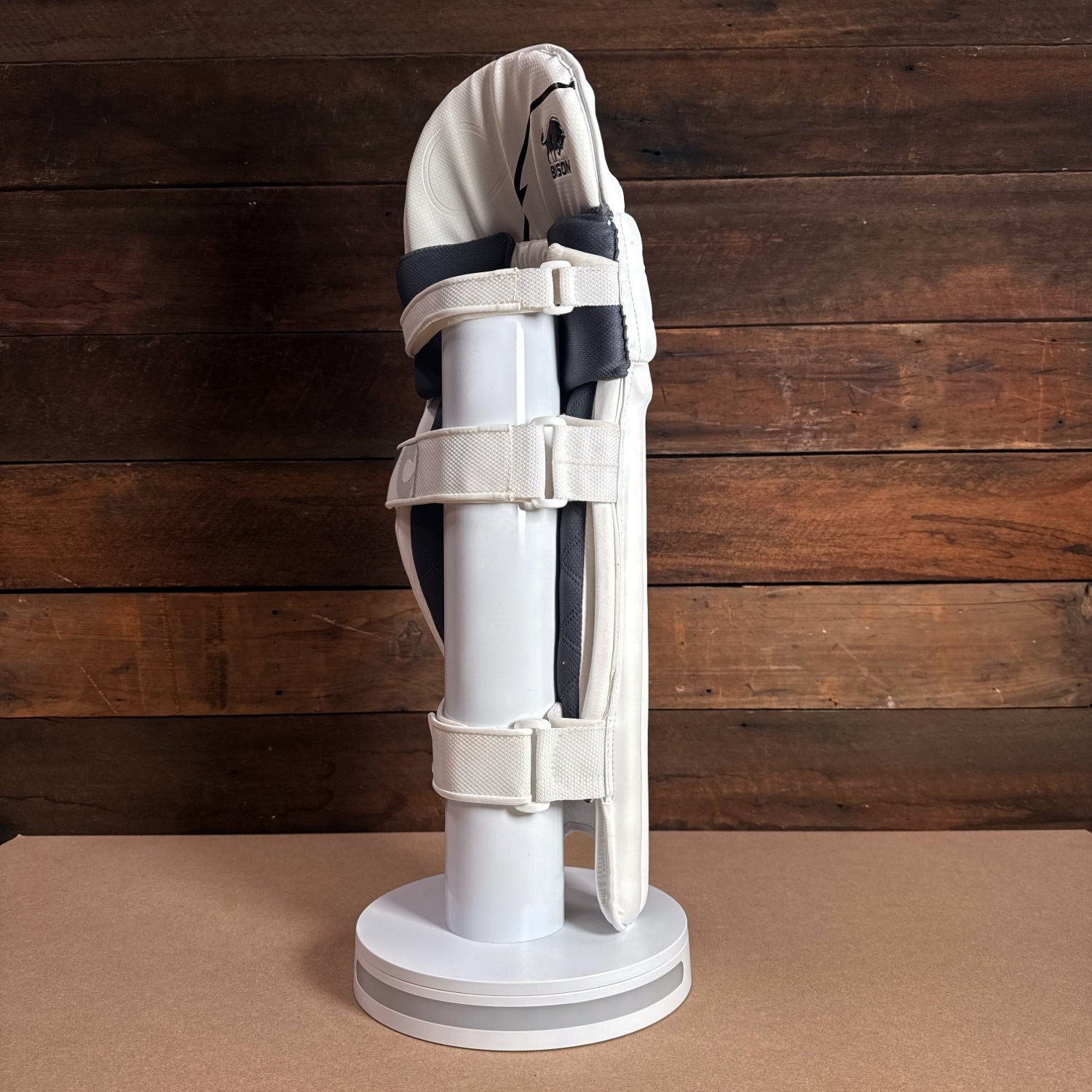 Bison cricket pads displayed on a stand, showcasing premium foam and secure fit for youth players.