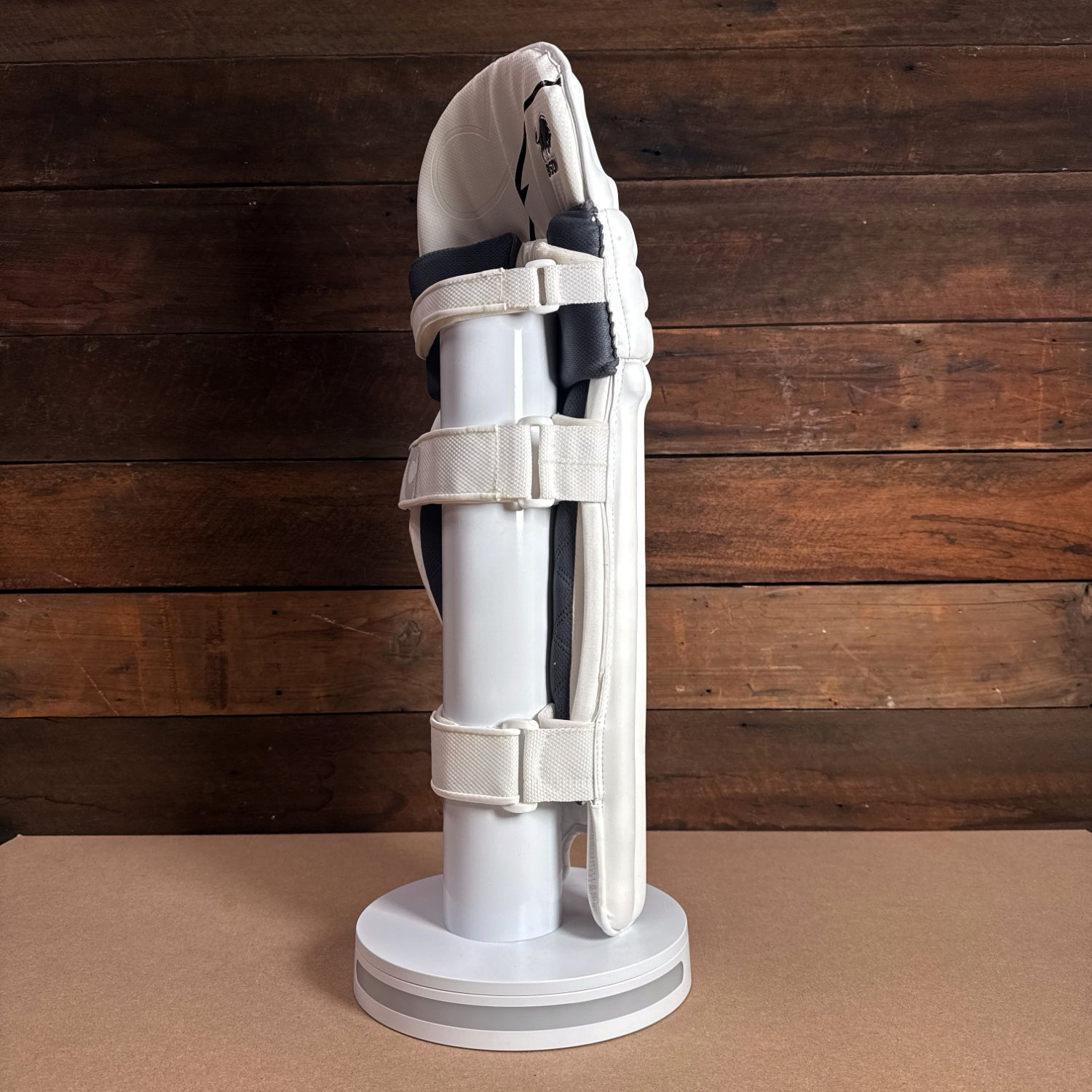 Bison Cricket Pads 2024-25 youth profile view showcasing premium foam and secure strap design on a display stand.