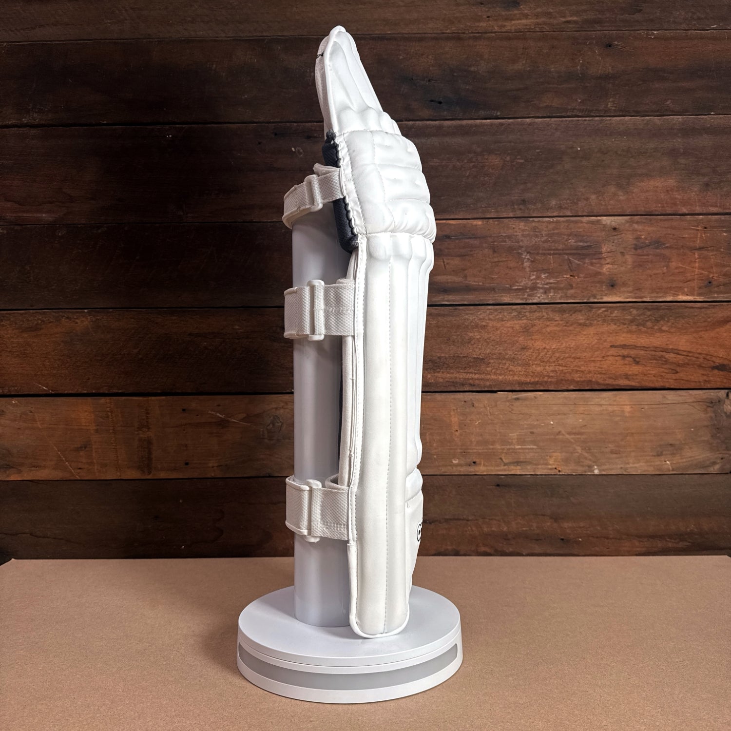 Bison Youth Cricket Pads showcasing premium protection and wraparound fit on display stand against wooden background.