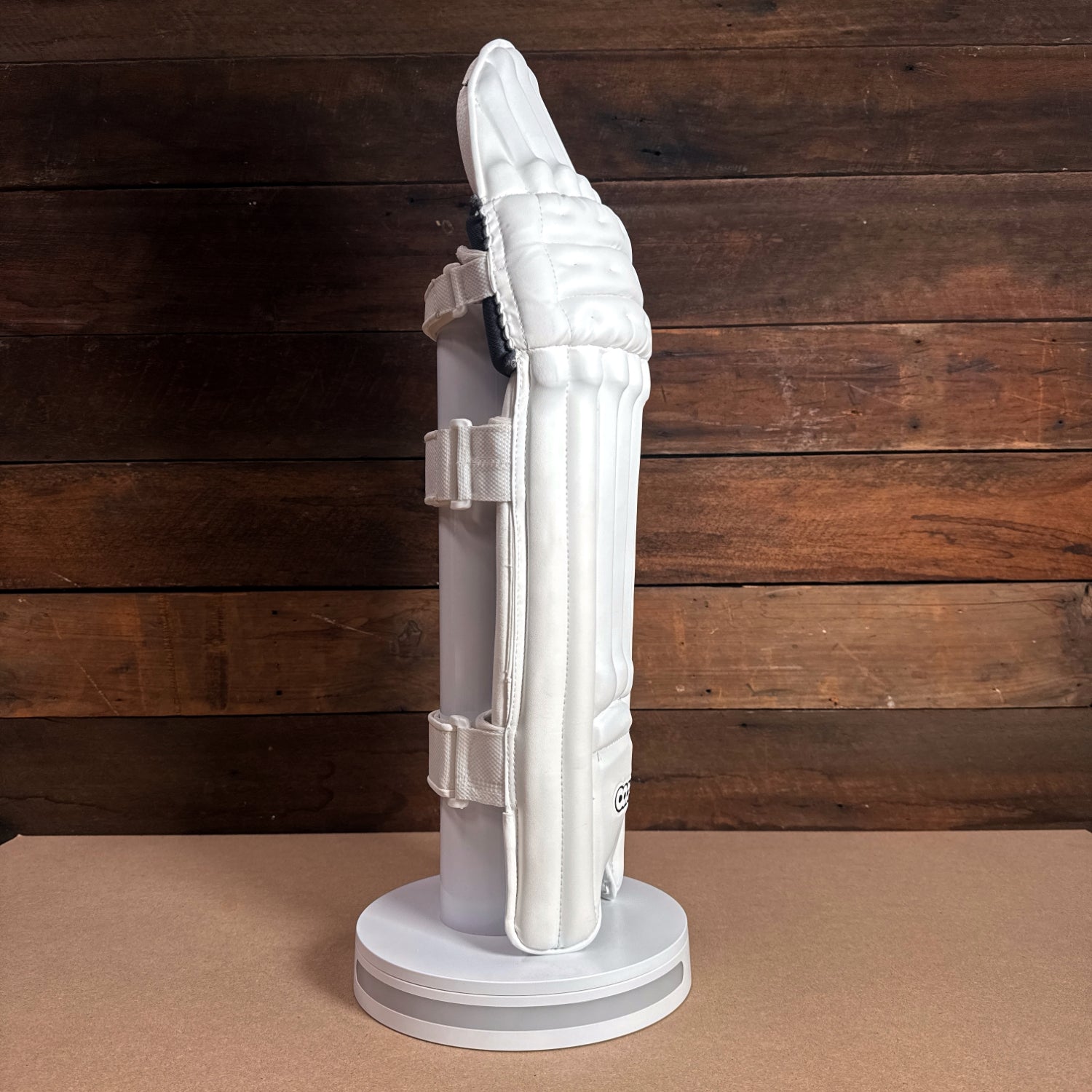 Bison youth cricket pads showcasing premium foam protection, designed for comfort and a snug fit, displayed on a circular stand.