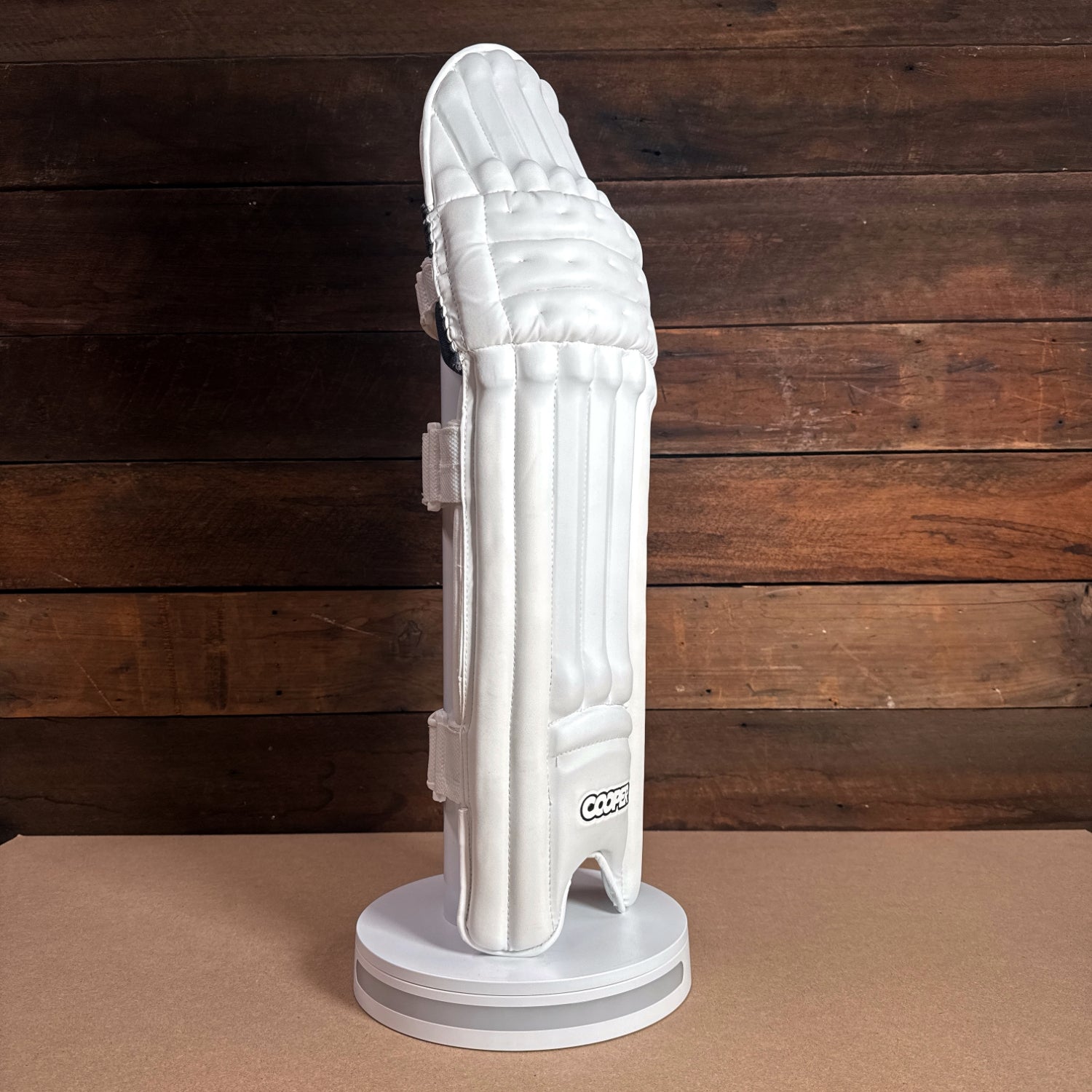 White Bison Cricket Pads 2024-25 displayed on a stand, showcasing premium protection and sleek design for youth players.