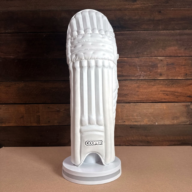 White cricket pad displayed on a stand, showcasing its sleek design and protective features.