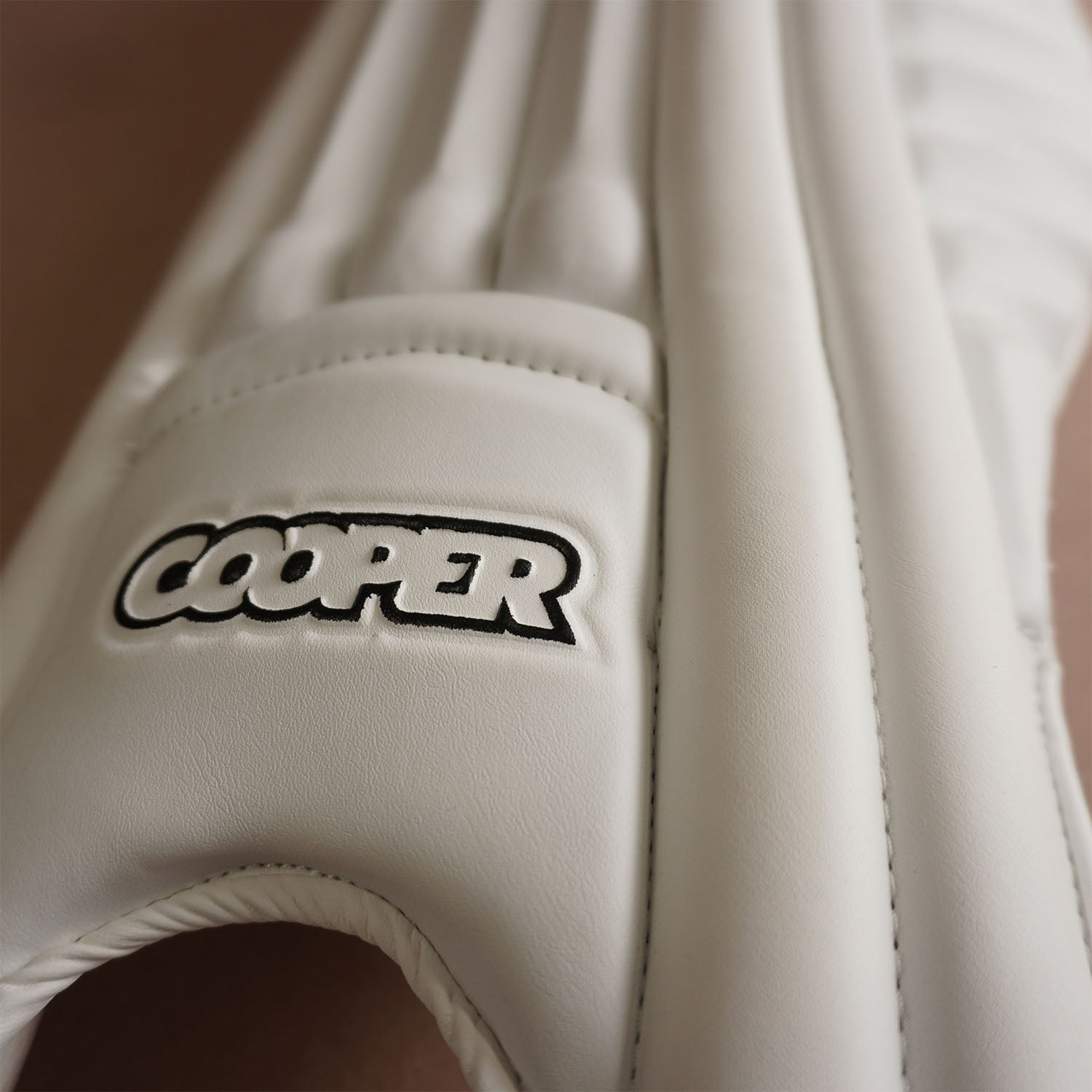 Close-up of a Cooper cricket pad showcasing its sleek design and premium white materials.