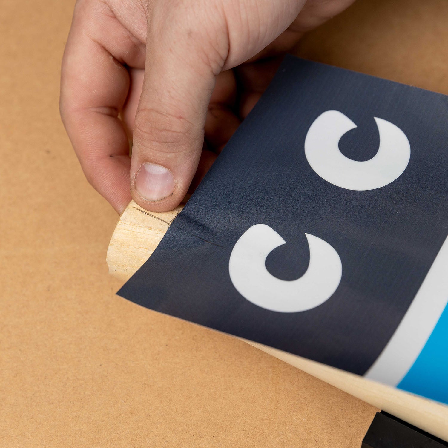 Hand applying custom cricket stump sticker for perfect alignment using a cricket stump marker tool.