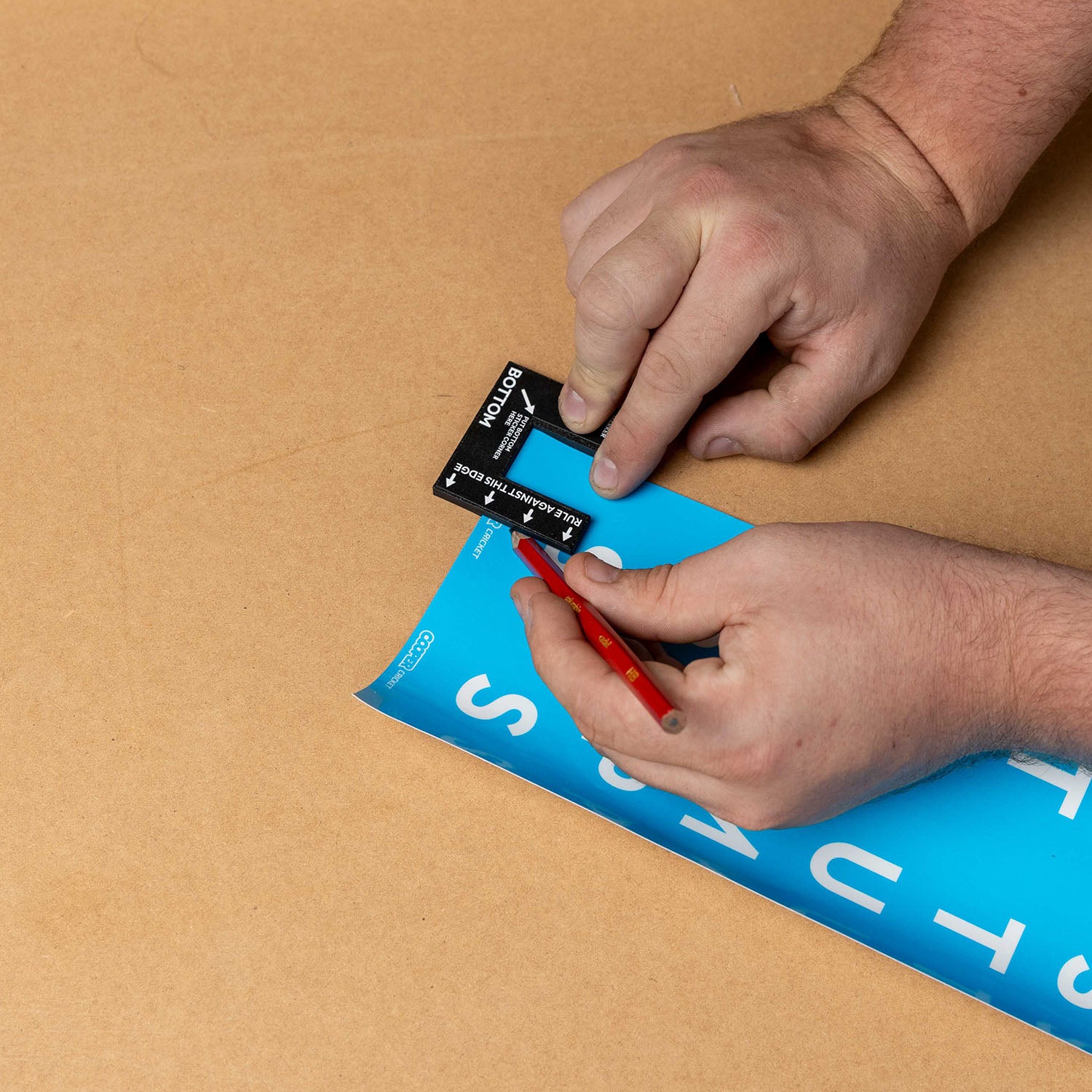 Person using cricket stump marker to align custom stump sticker on blue sheet for precise application.