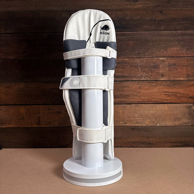 Bison youth cricket pads displaying premium foam protection and adjustable straps on a display stand.