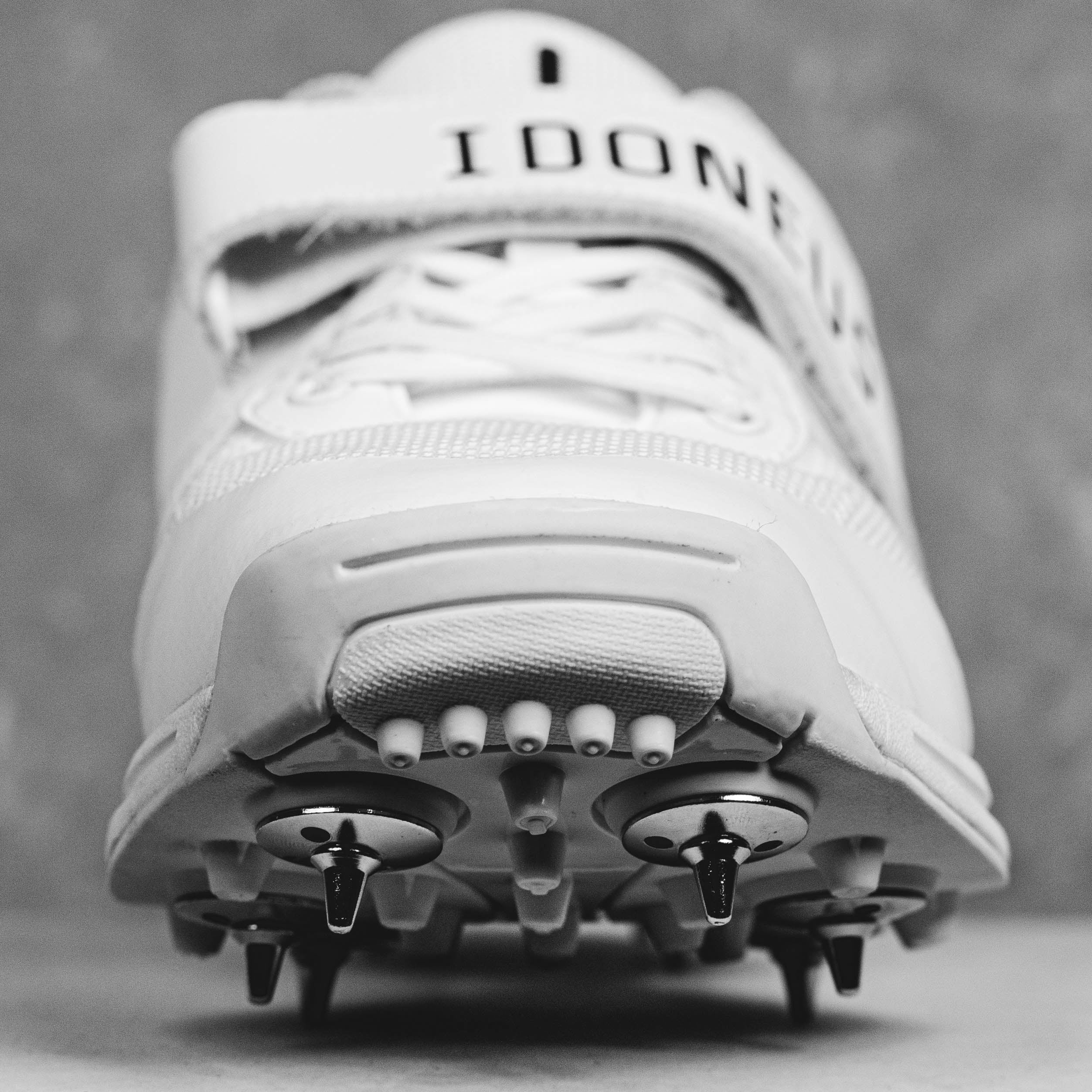 Close-up of Idoneus ID1 cricket shoe with steel spikes designed for superior grip and stability on various sports surfaces.