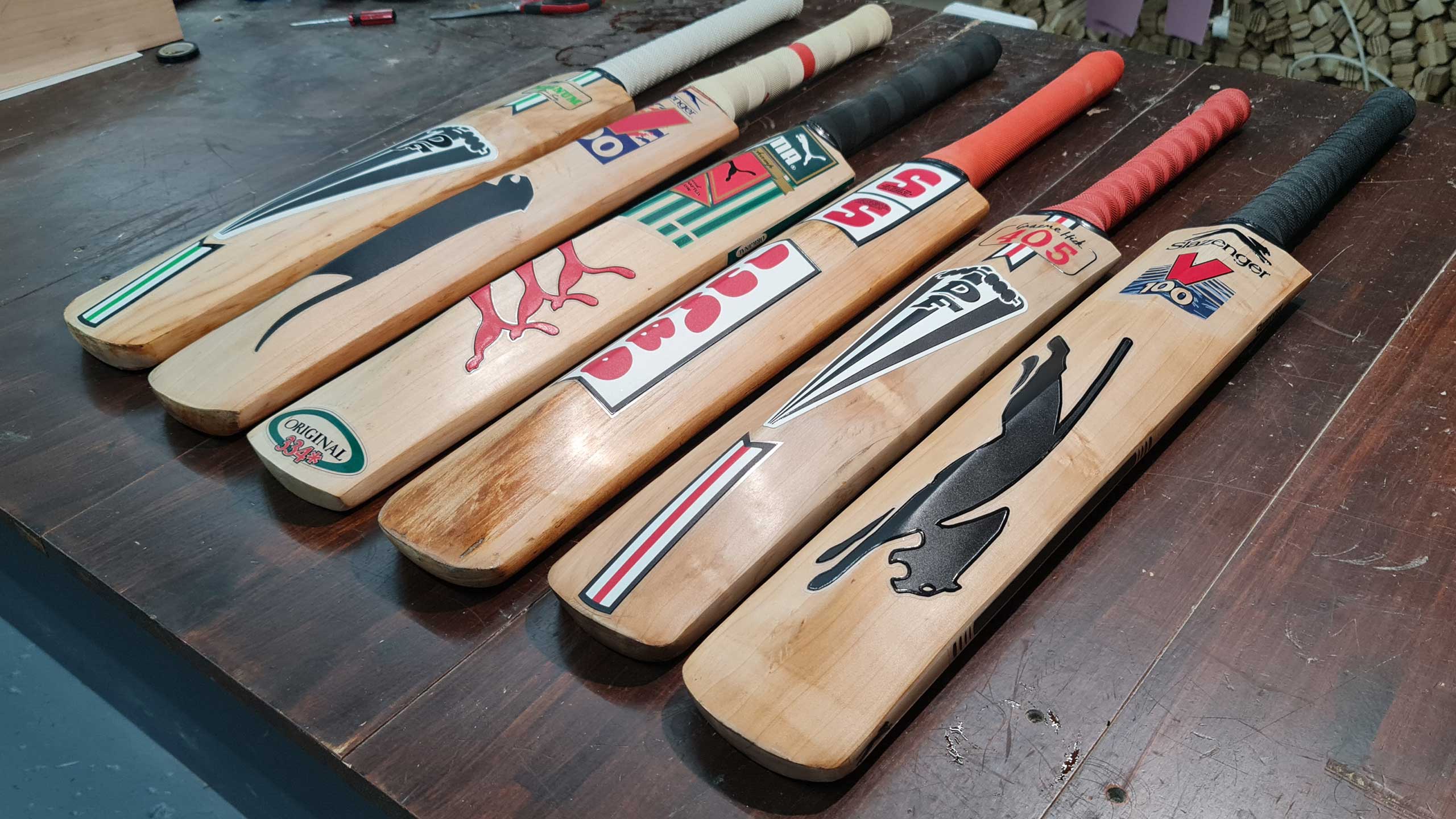 Restored vintage cricket bats lined up in the Cooper workshop